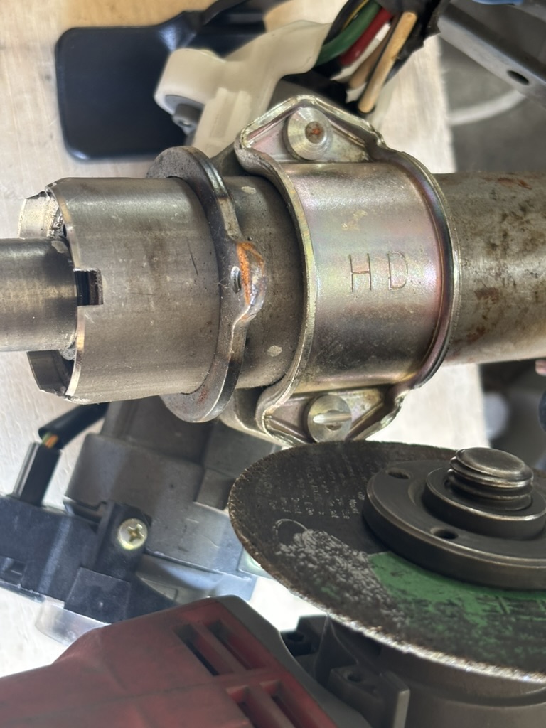 Cutting a flathead screwdriver slot into a steering column security bolt using a cut-off wheel.